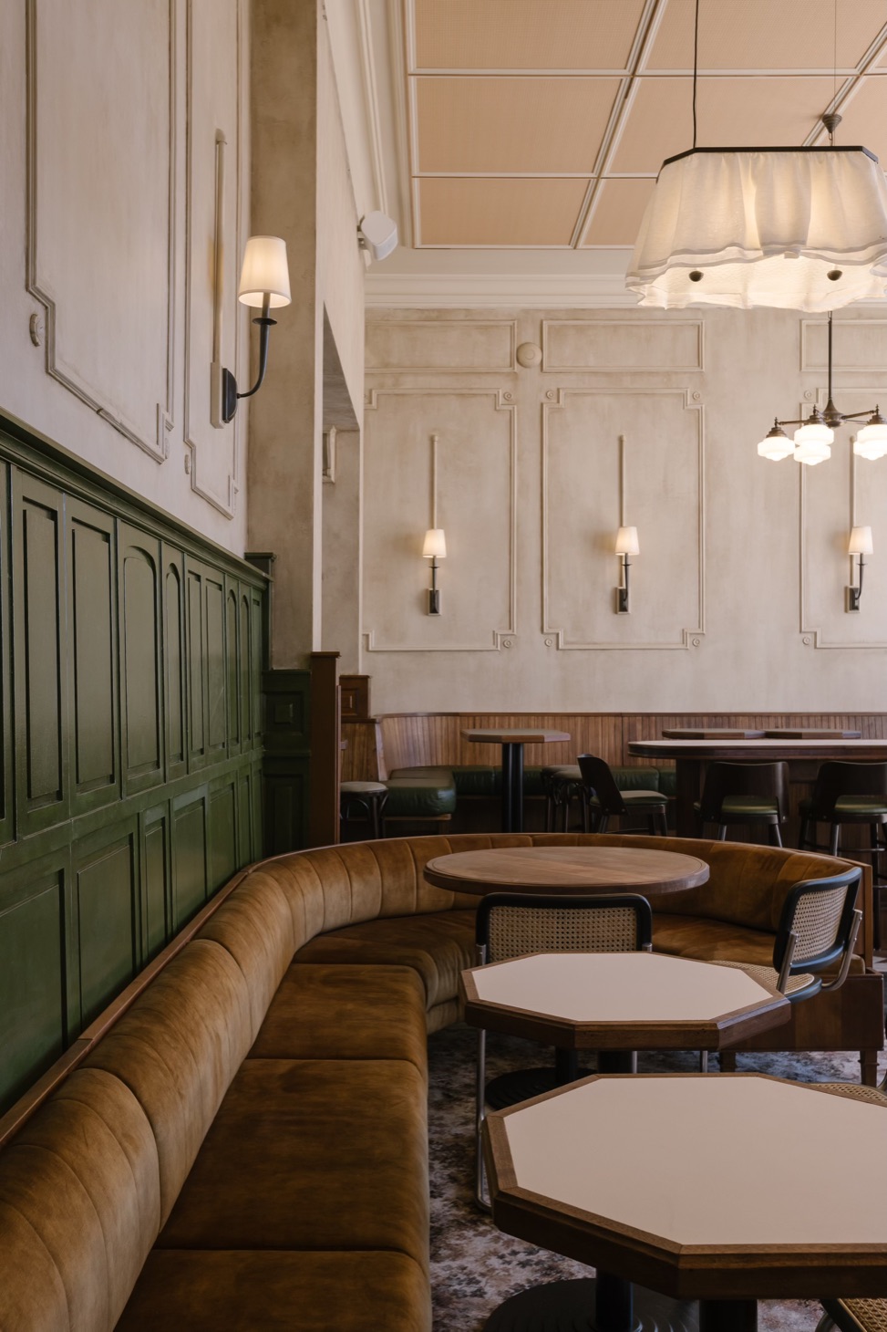 A long curved booth and octagonal tables beside the green panelling